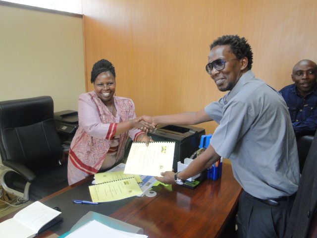 Jack Makau of the Kenya SDI Alliance and Hon. Esther Njuguna of Kiambu County Government exchange signed copies of the MOU.
